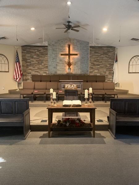 The pulpit, open Bible, and illuminated cross inside Faith Baptist Church.
